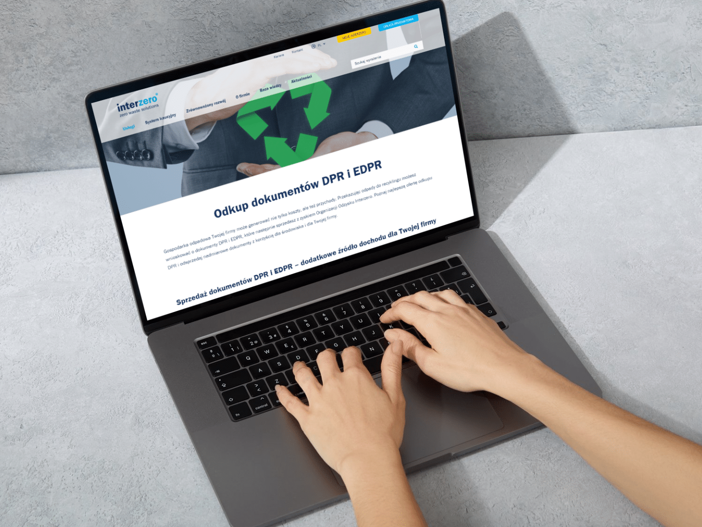 dłonie spoczywające na laptopie w tle widnieje podstrona interzero o odkupie dokumentów DPR i EDPR